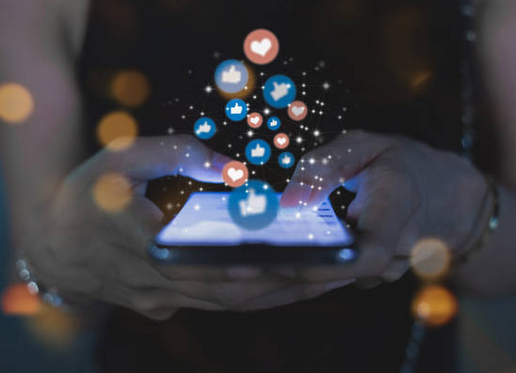 Imagem com um celular e saindo dele ícones de rede social como botões de like e amei